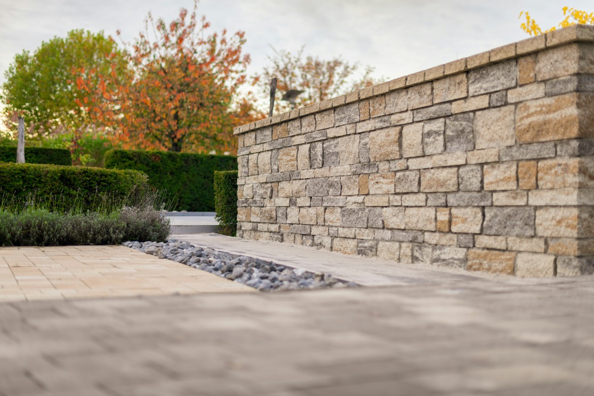 Dry-laid sandstone wall beside sandstone paving, a river-pebble strip, lavender and clipped hedges